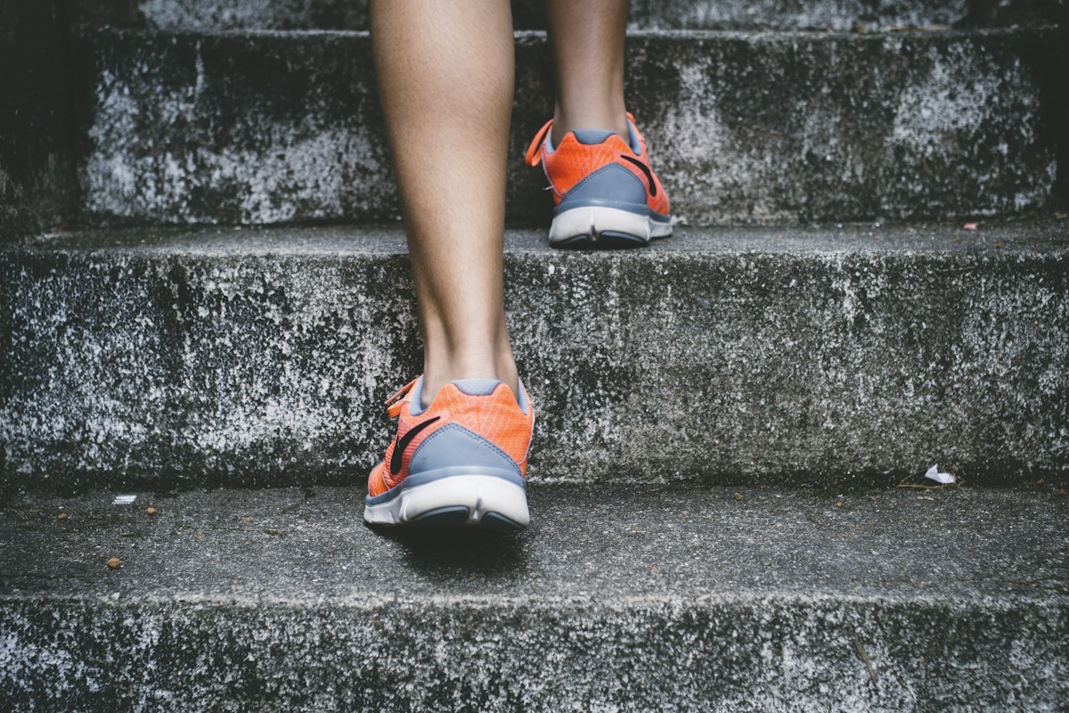 Person in running shoes moving up outdoor steps